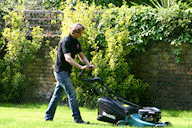 Handsome man mowing a lawn